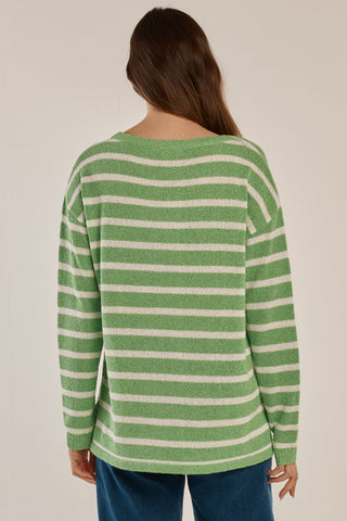 Back view of a woman wearing a green and white striped knit sweater and blue jeans.