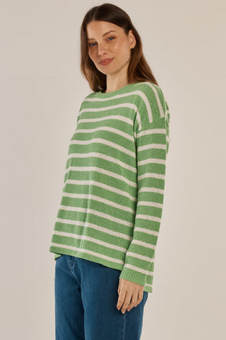 Woman wearing a green and white striped knit sweater and blue jeans.