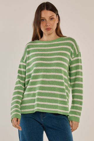 Woman wearing a green and white striped oversized knit sweater and blue jeans