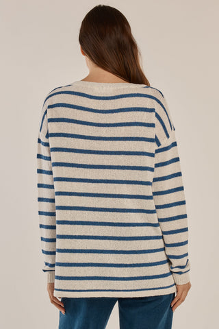 Rear view of a woman wearing a cream and blue striped knit sweater and blue jeans.