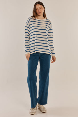 Woman wearing a cream and blue striped long sleeve sweater with wide leg blue jeans