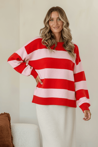 Woman wearing a red and pink striped oversized sweatshirt and white skirt.