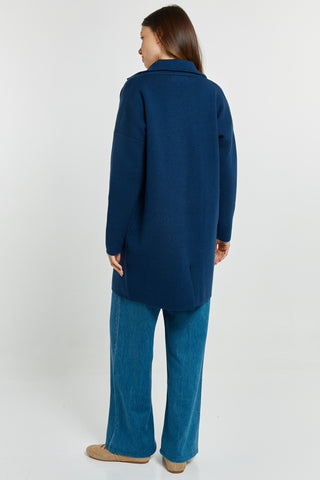 Woman wearing a navy blue longline coat and blue denim flare jeans.