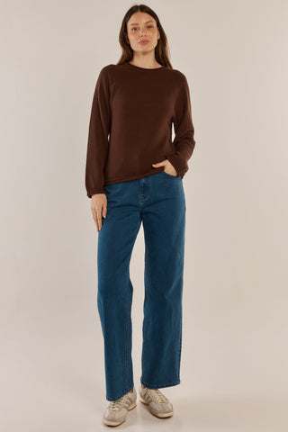 Woman wearing a brown long sleeve sweatshirt and blue wide leg denim jeans.