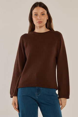 Woman wearing a brown long sleeve crewneck knit sweatshirt and blue denim jeans
