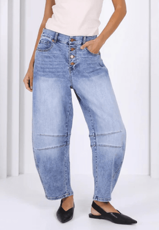 Woman wearing light wash blue wide-leg denim baggy pants and black pointed flats.