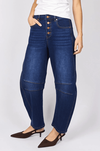 Woman wearing high-waisted dark blue button-front wide leg denim jeans and brown heels.