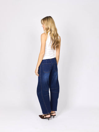 Woman in a white sleeveless top and wide-leg blue denim pants from a side rear view