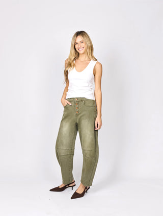 Woman wearing a white tank top and olive green utility pants with brown kitten heel pumps.