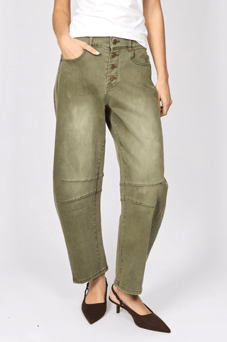 Woman wearing olive green high-waisted utility pants with button fly and pointed brown heels.