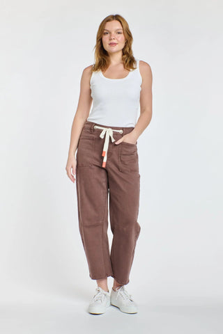 Woman wearing a white ribbed tank top and brown Homelee apartment pants with drawstring waist.
