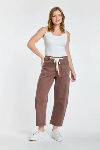 Woman wearing brown wide-leg drawstring pants and a white tank top.