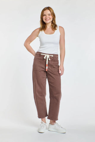 Woman wearing brown wide-leg drawstring pants and a white ribbed tank top.