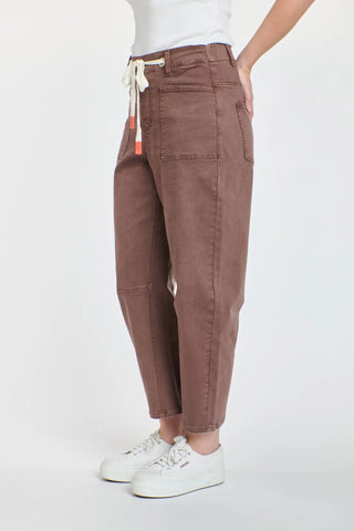 Woman wearing brown high-waisted drawstring lounge pants and white sneakers.