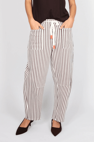 Woman wearing white and brown vertical striped lounge pants with a drawstring waist.