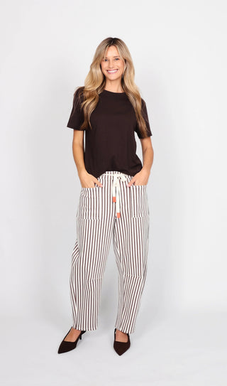 Woman wearing a brown t-shirt and vertical striped linen pants with a drawstring waist.