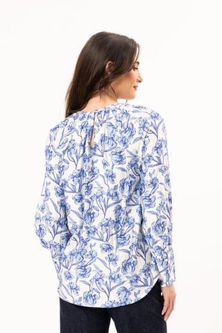 Rear view of a woman wearing a white long-sleeved blouse with a blue floral print.