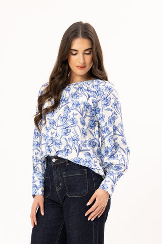 Woman wearing a blue and white floral print long sleeve blouse and dark blue jeans