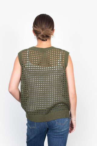Back view of a woman wearing an olive green open-knit sleeveless sweater and blue jeans.