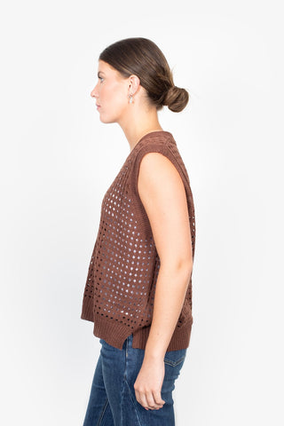 Woman in profile wearing a brown sleeveless open-knit crochet top and blue jeans.