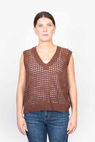 Woman wearing a brown crochet knit sleeveless V-neck top and blue denim jeans.