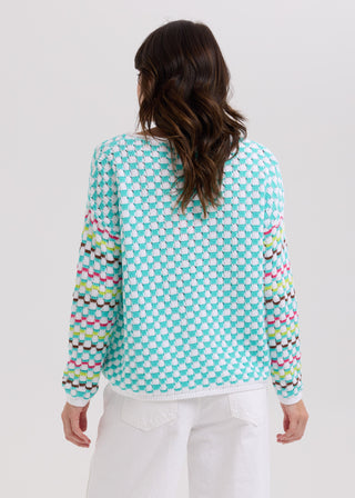 Rear view of a woman wearing a blue and white checkered knit sweater with colorful striped sleeves.