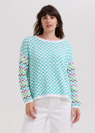 Woman wearing a turquoise and white checkered knit sweater with colorful striped sleeves.