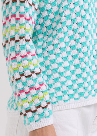 Close-up of a multi-colored textured knit sweater with turquoise, pink, and brown patterns.