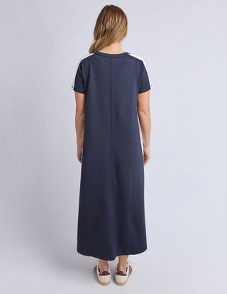 Back view of a woman wearing a navy blue maxi dress with white stripe details.