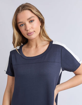 Woman wearing a navy blue short sleeve t-shirt with white shoulder stripe details.