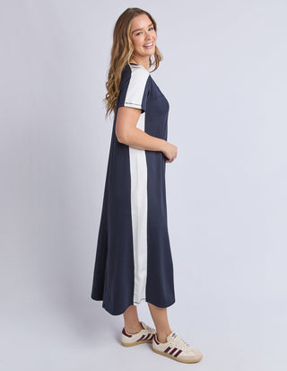 Woman wearing a navy blue and white side-stripe midi dress with casual sneakers.