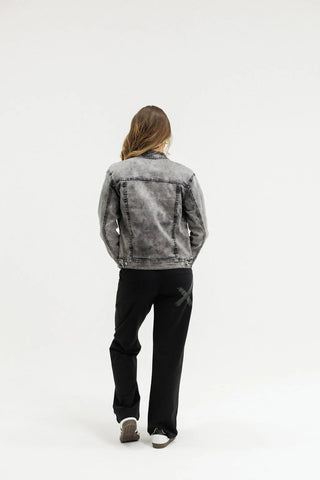 Woman wearing a grey acid wash denim jacket and black wide-leg pants.