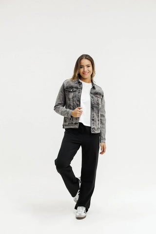 Woman wearing a grey denim jacket over a white t-shirt and black wide-leg pants.