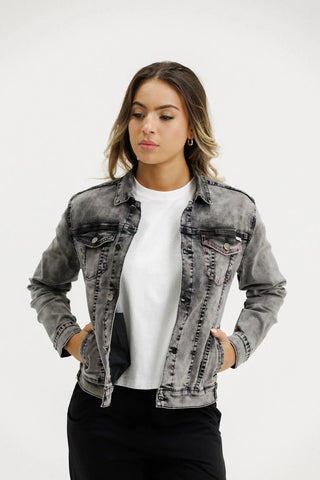 Woman wearing a grey washed denim jacket over a white t-shirt.