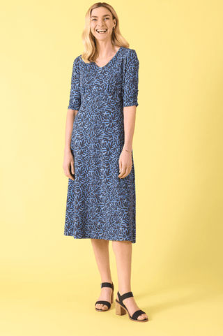 Woman wearing a blue and navy patterned midi dress and black block-heel sandals.