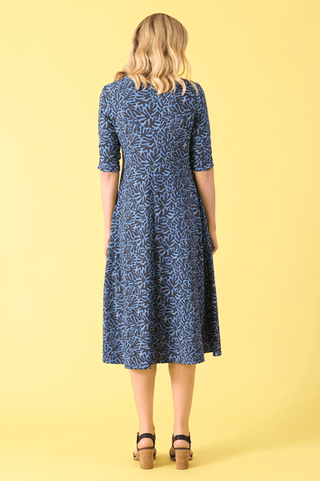 Back view of a woman wearing a blue and navy patterned midi dress and black sandals
