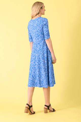 Woman wearing a blue geometric print midi dress and black block heel sandals