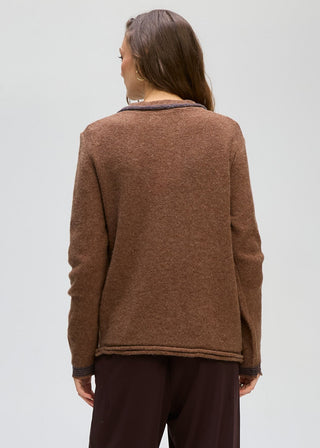 Woman wearing a brown textured long sleeve coatigan and dark trousers.