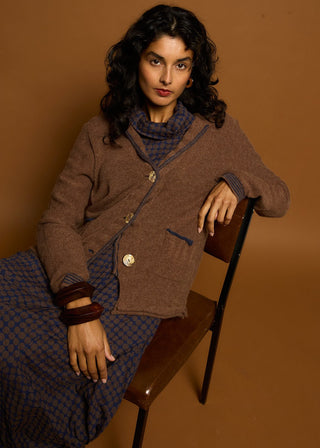 Woman wearing a brown textured cardigan over a blue patterned maxi dress.