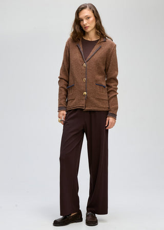 Woman wearing a brown textured coatigan over a dark top and wide-leg maroon trousers.