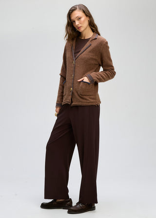 Woman wearing a brown textured cardigan over a dark top and wide-leg brown trousers.