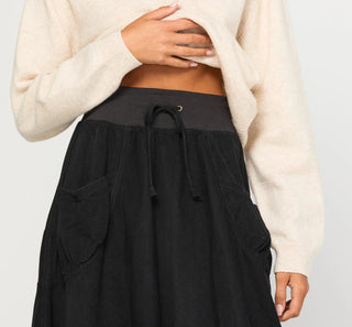 Woman wearing black drawstring lounge skirt and cream knit sweater.