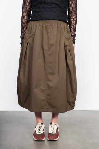 Woman wearing a brown midi skirt with pleats and lace black long sleeve top.