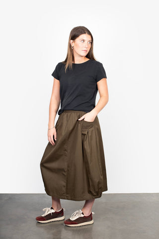 Woman wearing a black t-shirt and olive green midi skirt with pockets.