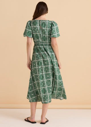 Woman wearing a green patterned midi summer dress with short puff sleeves.