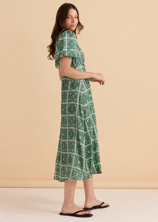 Woman wearing a green patterned midi summer dress and black flip flops