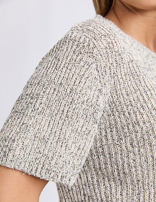 Close-up of a woman wearing a textured, marled grey and white knit short-sleeve top.