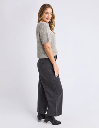Woman wearing a textured grey short sleeve knit top and wide leg black jeans.