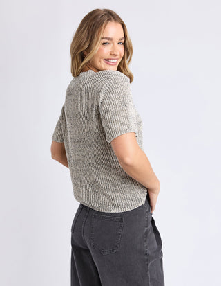 Woman wearing a grey textured short sleeve knit top and dark grey wide leg jeans.