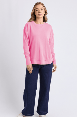 Woman wearing a pink oversized sweatshirt and wide-leg navy blue jeans.